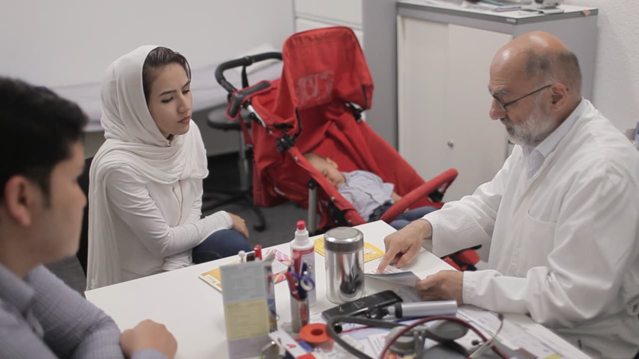 Das Bild zeigt eine Familie mit ihrem Kleinkind bei einem Arzt. Das Kleinkind ist im Kinderwagen. Die beiden Eltern unterhalten sich mit dem Arzt.