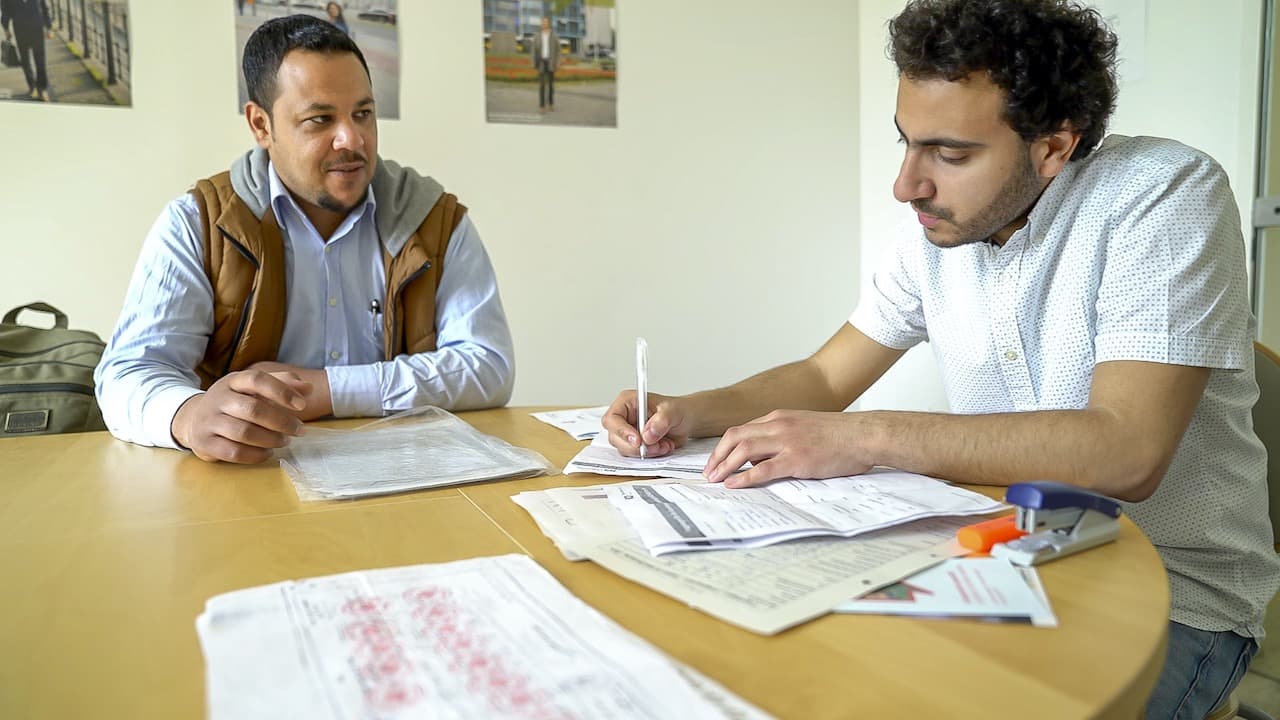 A person stitting next to a counsellor who is filling some forms