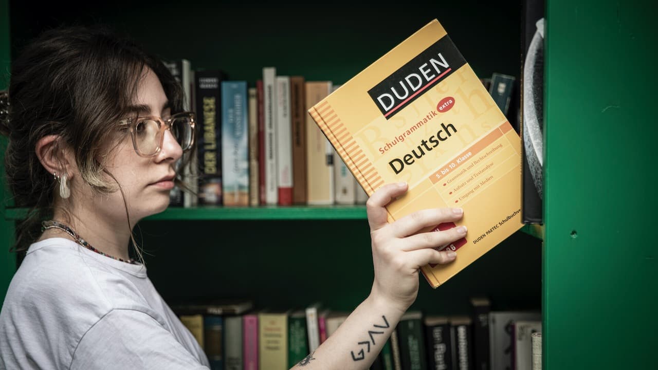 Women taking a German grammar book from bookshelf
