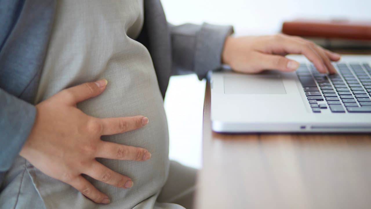 A pregnant person sitting in front of a laptop
