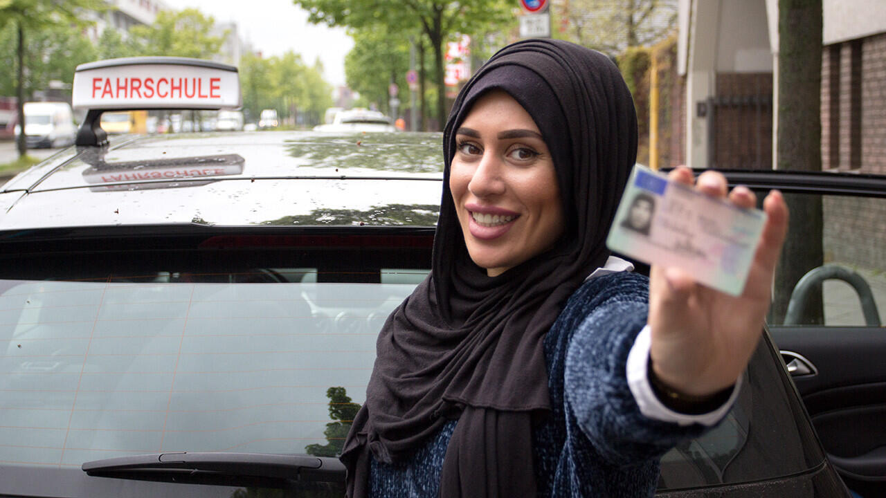Auf dem Bild hält eine Fahrerlehrerin ihren Führerschein in die Kamera. 