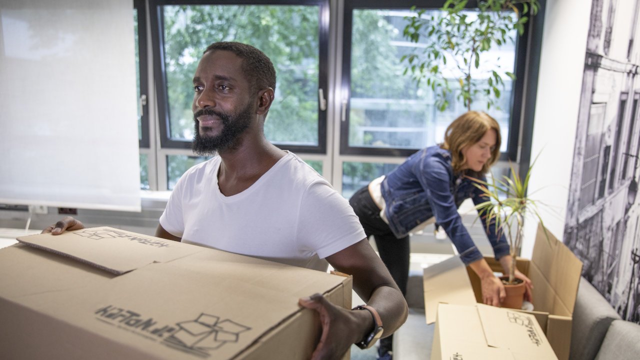 Eine weiblich gelesen Person und eine männlich gelesene Person beim Packen von Umzugskisten.