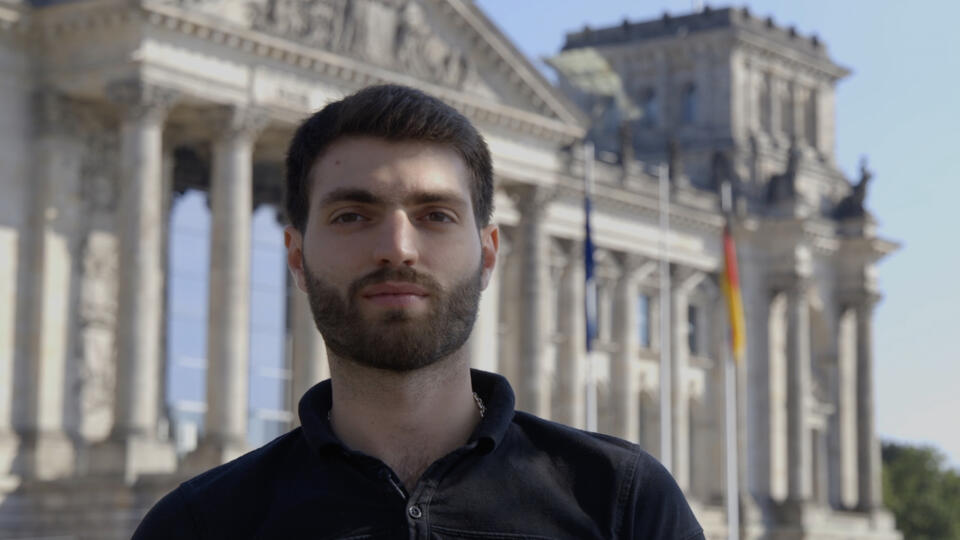 Das Bild zeigt einen jungen Mann vor dem Bundestagsgebäude.