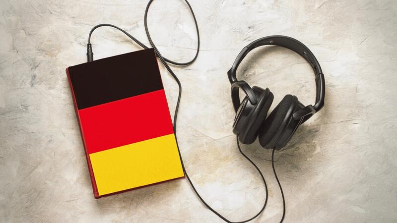 Das Bild zeigt einen Kopfhörer, der an einem sehr großen MP3-Player in Deutschlandfarben angestöpselt ist.